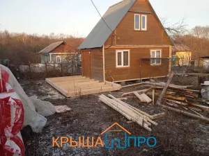 Каркас пристройки из бруса рядом с домом, обёрнутым гидроветрозащитой