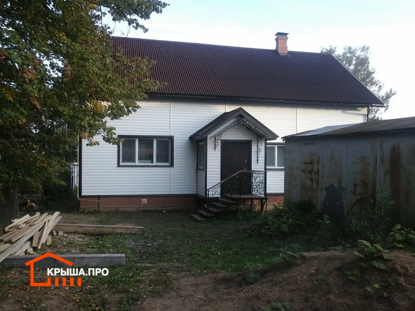 Отделка фасада сайдингом Döcke в селе Раменье: 225 м² за полторы недели — объект №17 - Фото 7 Главный фасад дома с крыльцом, обшитый сайдингом Döcke цвета пломбир, с коричневым водостоком