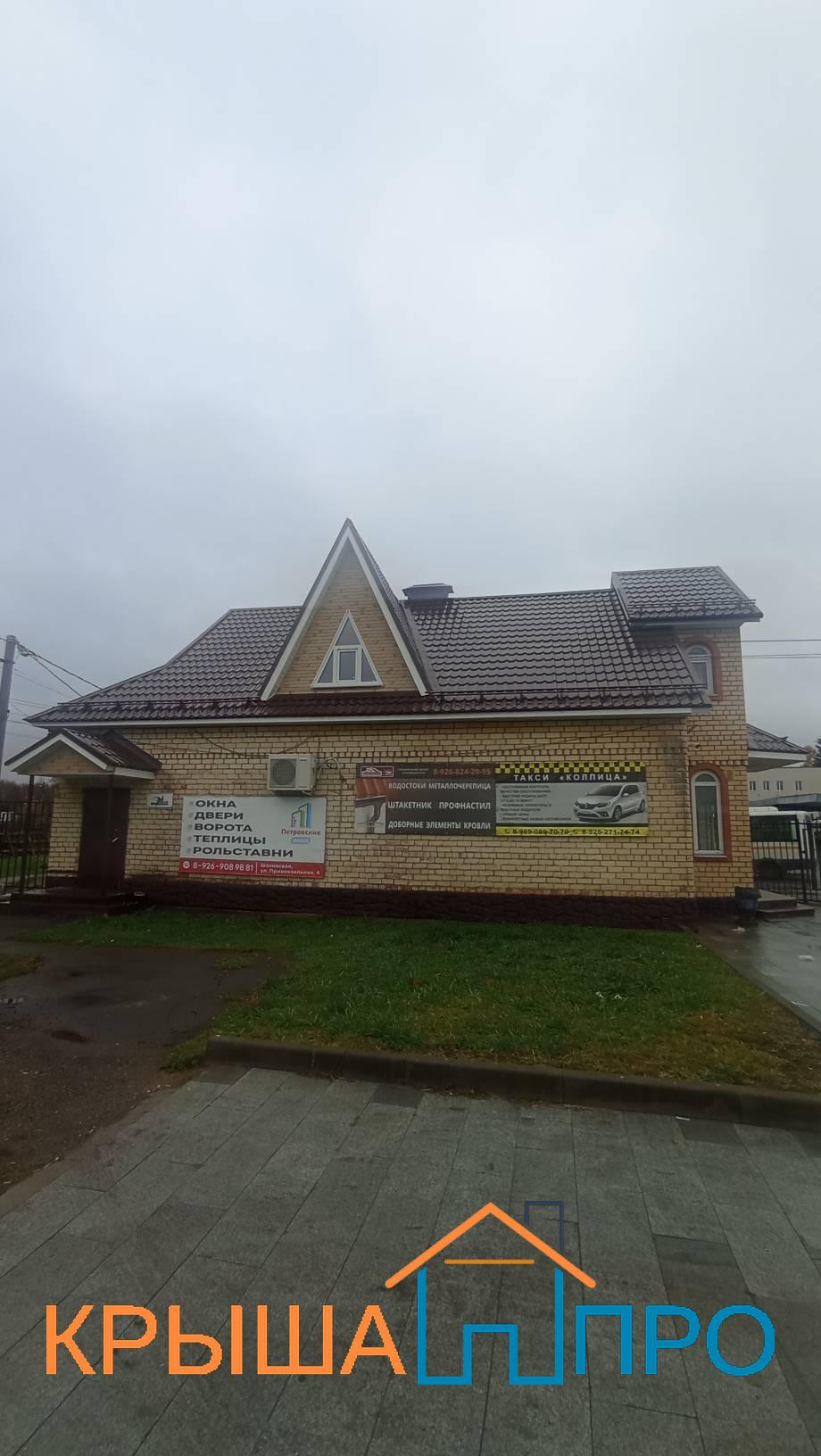 Фронтон магазина в Шаховской, обшитый фасадными панелями под кирпич, с белыми планками и чердачным окном
