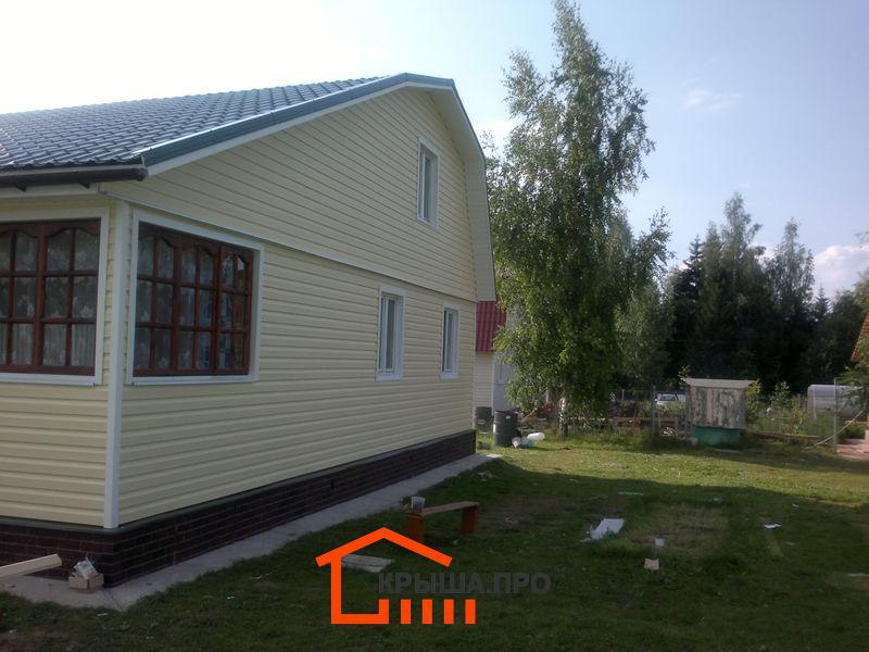 Фасад дома с сайдингом и цоколем под кирпич, веранда в процессе обшивки