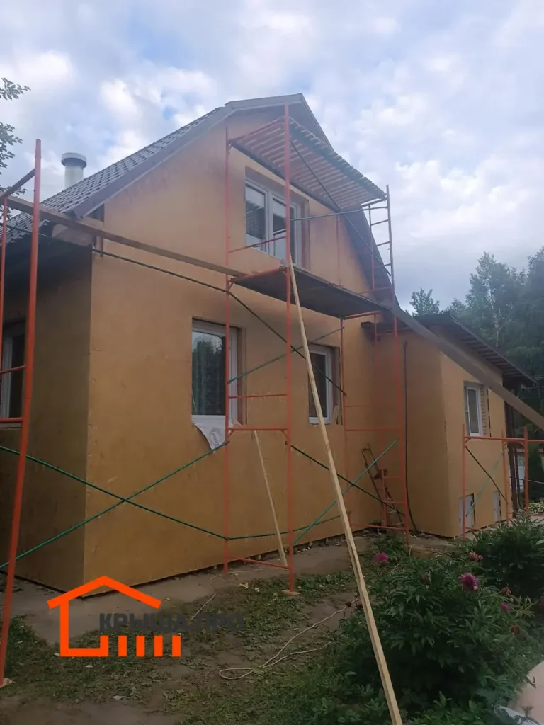 Строительные леса у оштукатуренной стены дома перед монтажом фасадной плитки