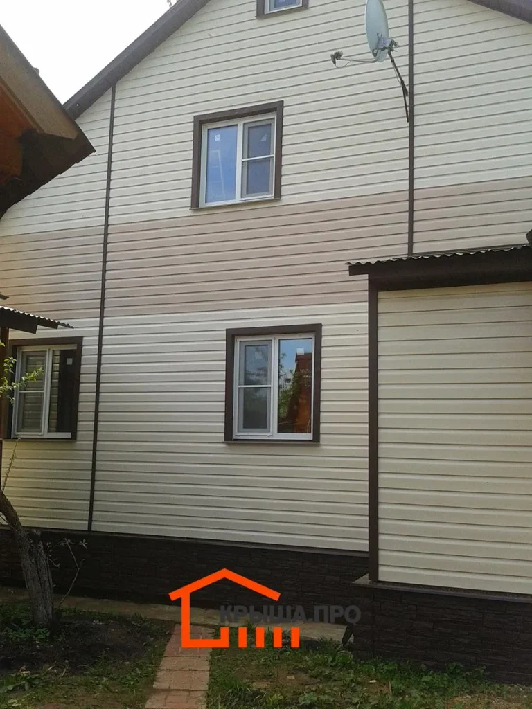 Отделка дачного дома сайдингом Holzplast в СНТ «Руза»: 195 м² за две недели — объект №8 - Фото 5 Фасад дома с горизонтальным поясом из светло-бежевого сайдинга между этажами