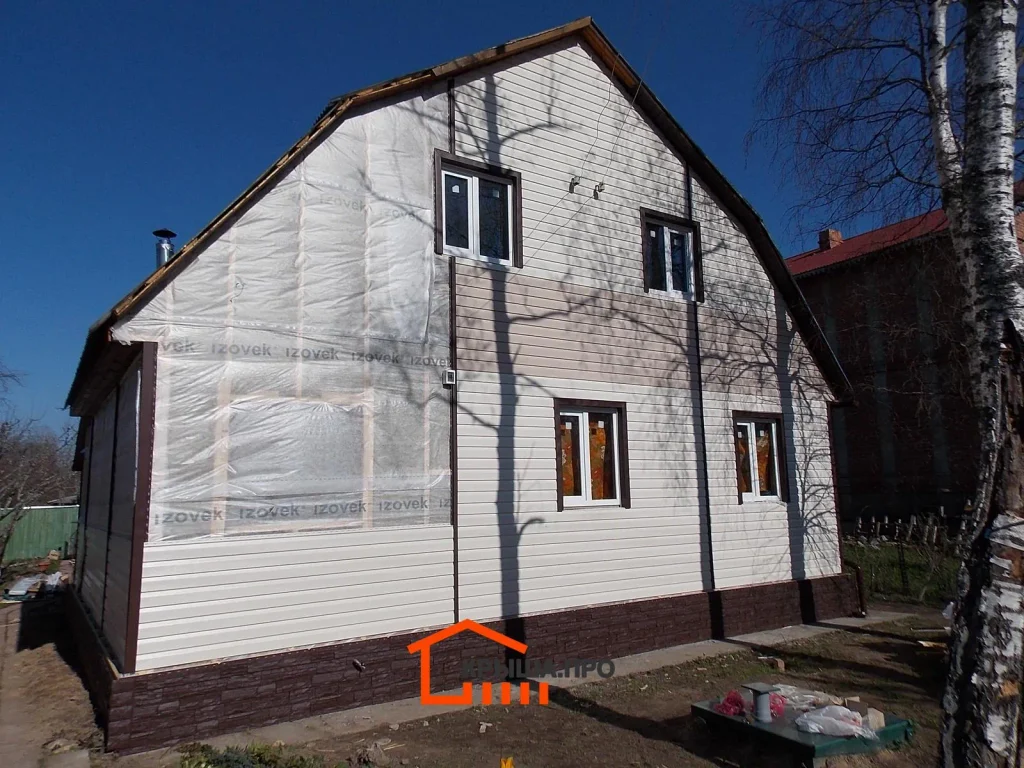 Отделка дачного дома сайдингом Holzplast в СНТ «Руза»: 195 м² за две недели — объект №8 - Фото 11 Дом в процессе обшивки: новые пластиковые окна, ветрозащита на фронтоне, часть сайдинга уложена