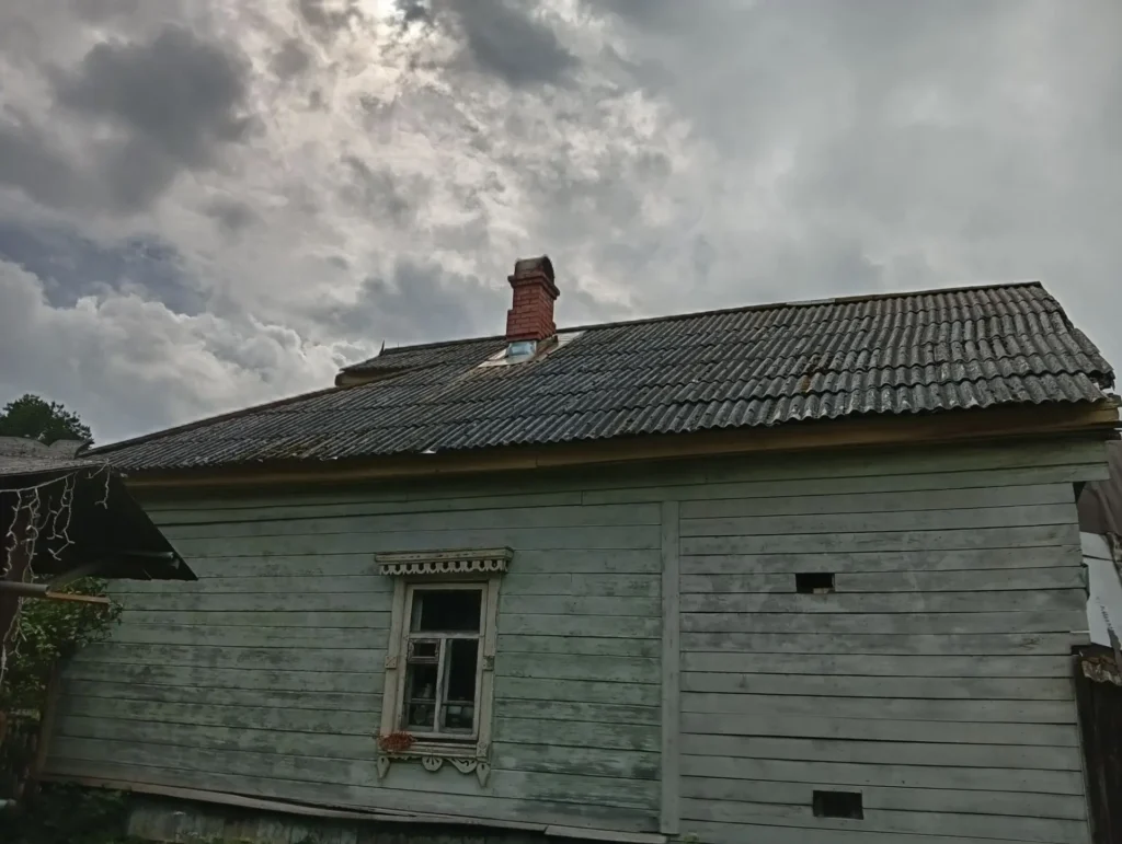 Старая шиферная крыша деревянного дома, покрытая мхом